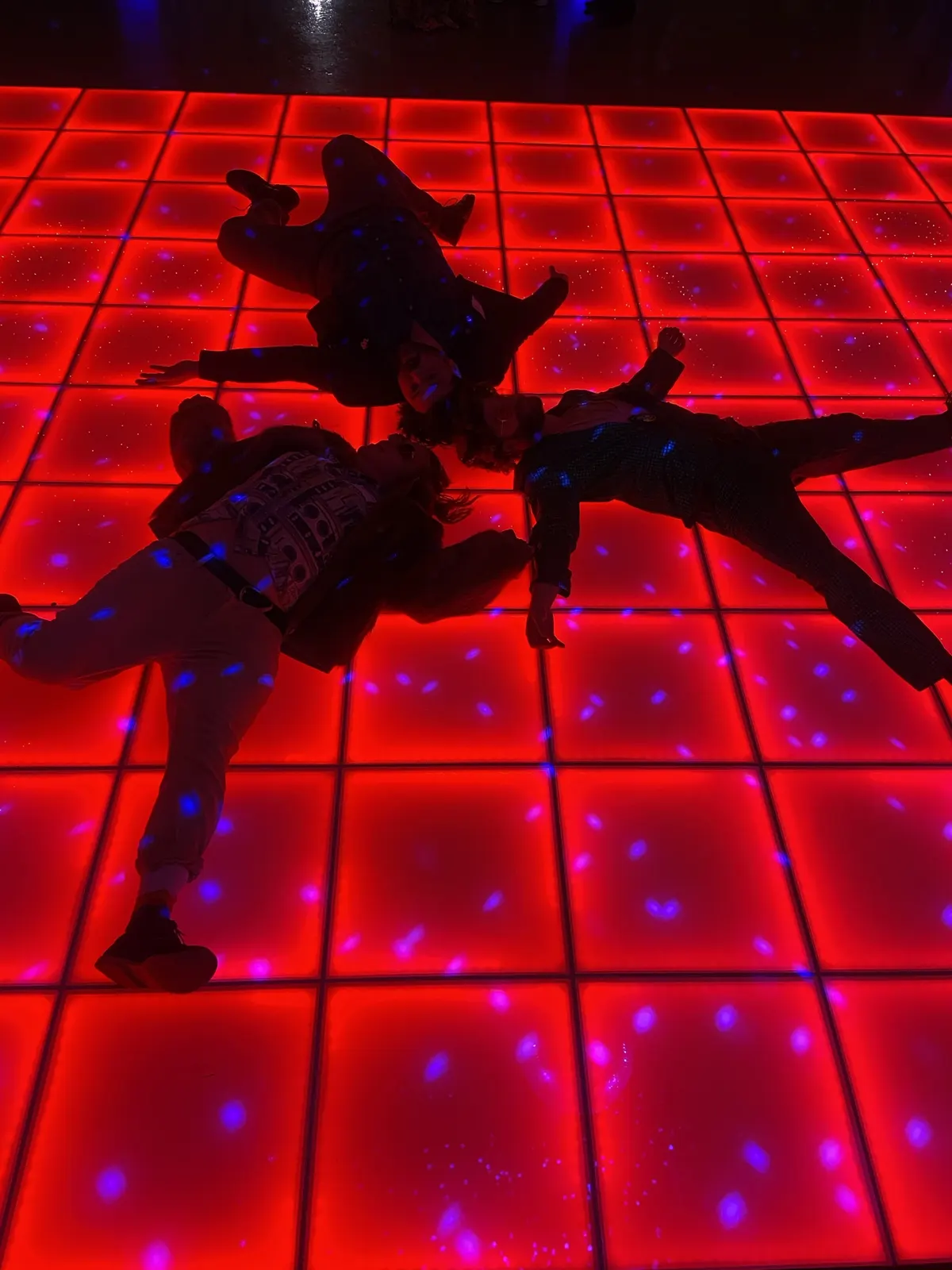 Three guests sprawled like bodies on a glowing red disco floor